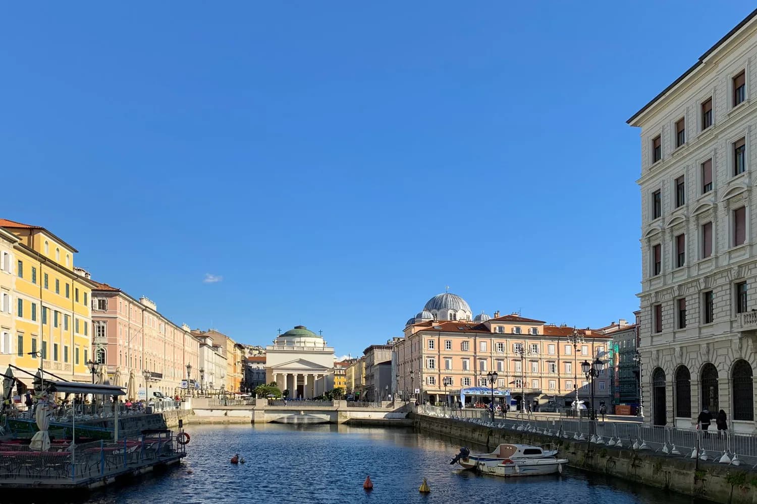 Kanalblick auf die historische Altstadt von Triest mit klassizistischer Kirche und bunten Gebäudefassaden am Ufer