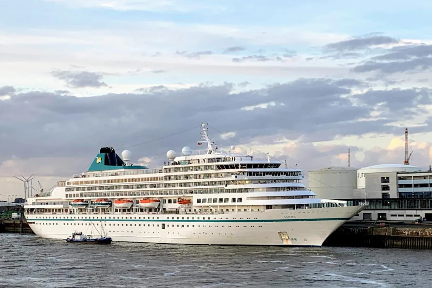 Weißes Kreuzfahrtschiff mit türkisfarbenem Schornstein liegt am Kreuzfahrtterminal im Hafen von Bremerhaven