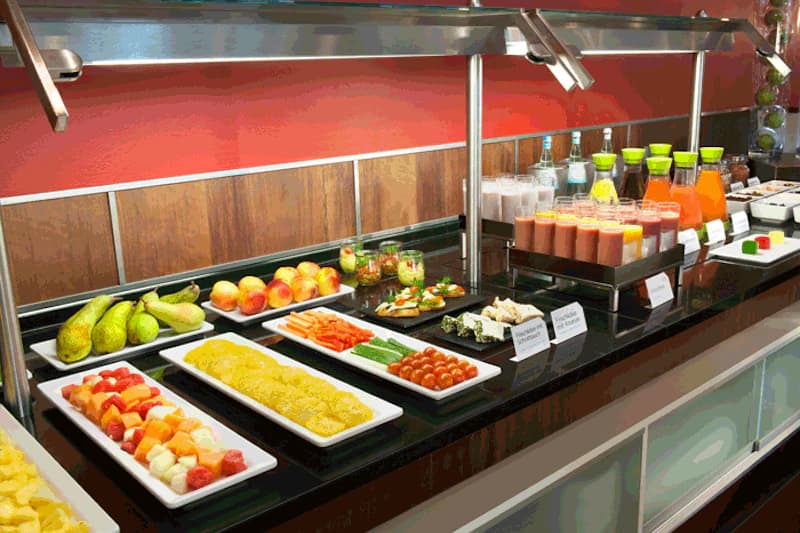 Buffet mit Tellern voller Obst, Gemüsesticks, kleinen Häppchen und Karaffen mit Säften.