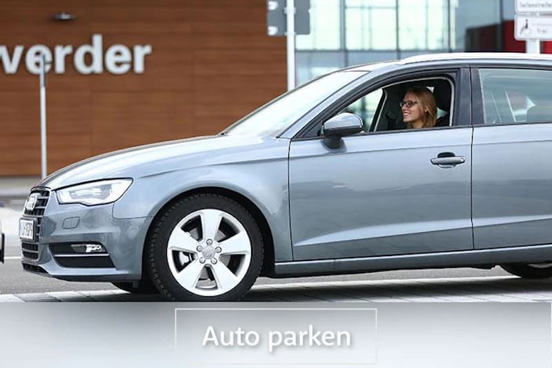 Graues Auto mit Fahrerin vor einer Fassade mit dem Schriftzug werder.