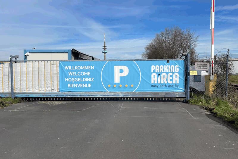 Schiebetor mit blauem Parking Airea Banner, Maschendrahtzaun, Schranke und Zufahrtskontrolle am Hafen Köln.