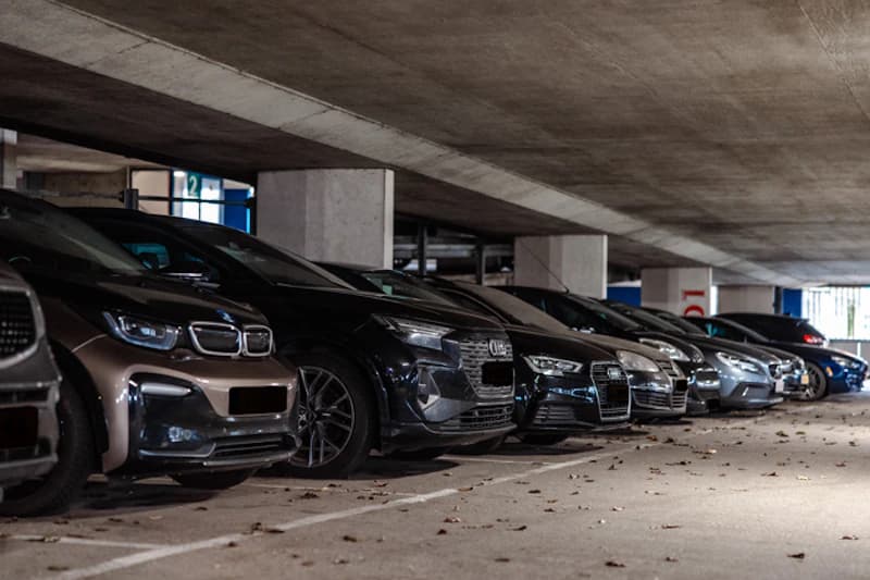 Reihe geparkter Autos in einer niedrigen Beton-Parkhalle mit Stützpfeilern.