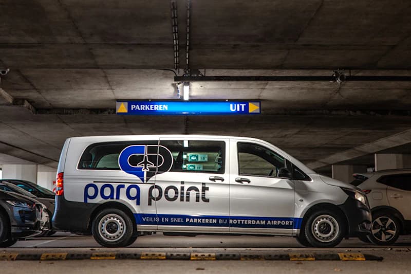 Weißer Parq Point Transporter in einer unterirdischen Parkhalle unter blauem Parken-Ausgangsschild.