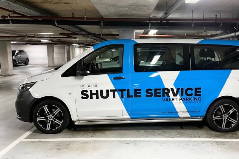 weißer und blauer Shuttlebus mit Schriftzug SHUTTLE SERVICE in einer Tiefgarage.